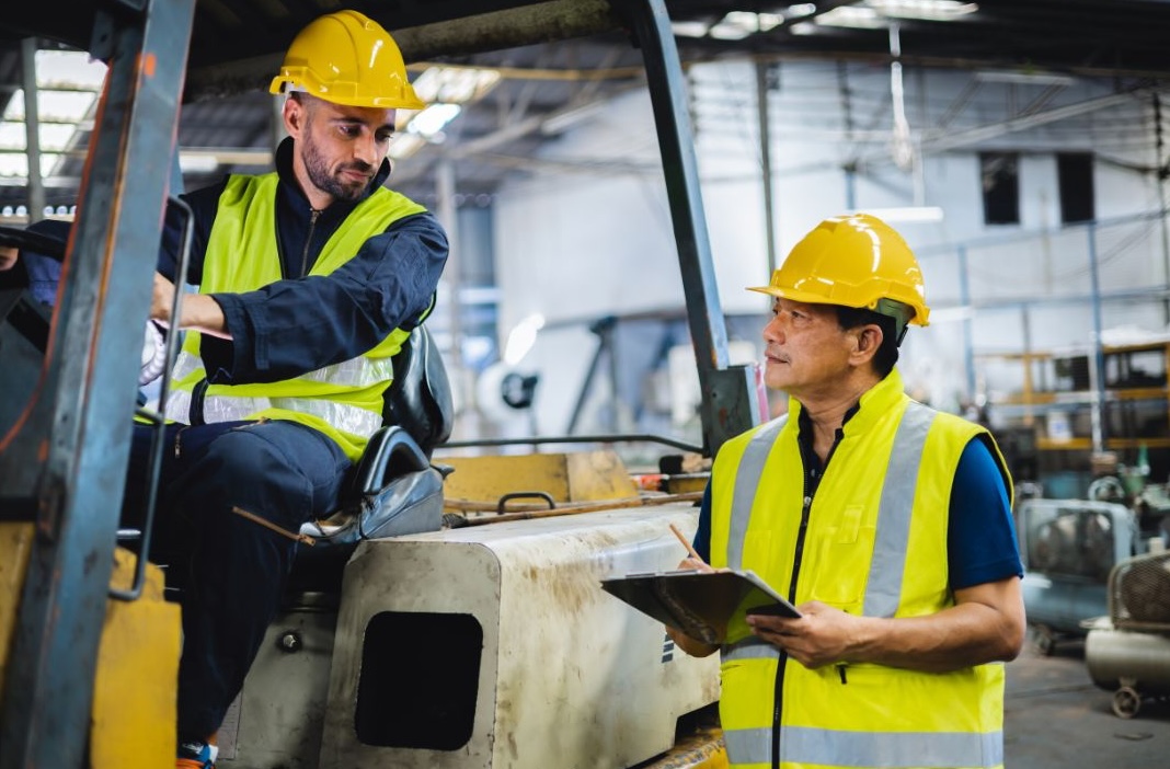 a man in yellow safety vests and yellow hard hats sitting on a machine